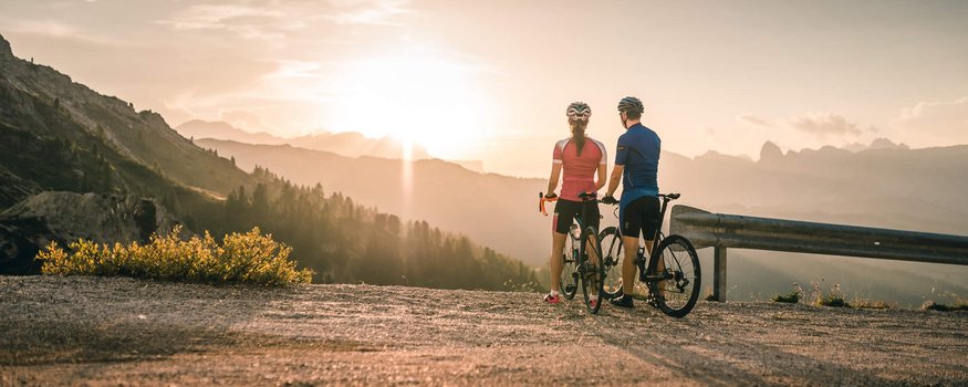 Hotel Melodia del Bosco **** © Molography Zwei Radfahrer blicken bei Sonnenuntergang auf Berge