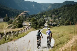 Vacanze in bici da corsa in Slovenia © Alain Rumpf Due ciclisti su strada di campagna accanto a binari ferroviari in zona montuosa