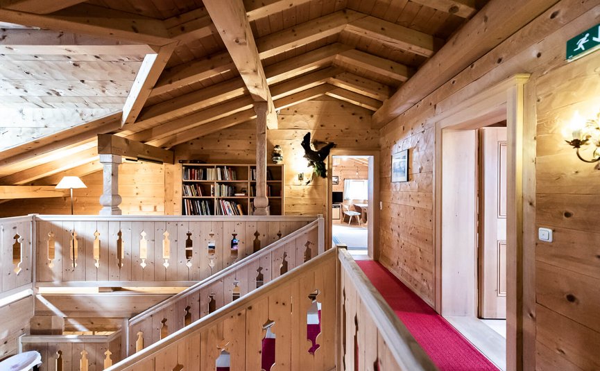 Innenansicht eines holzverkleideten Dachgeschosses mit Treppe und Bücherregal