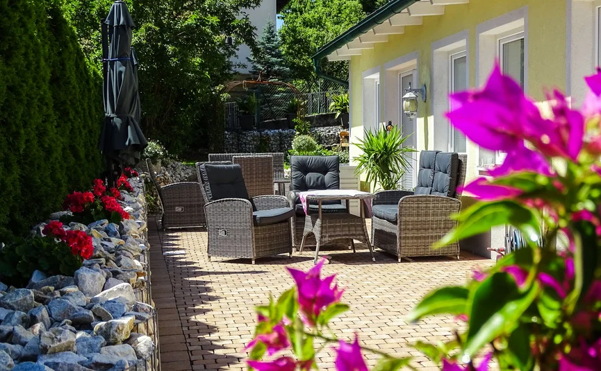 Sunny patio with garden furniture and flowers in front of a house