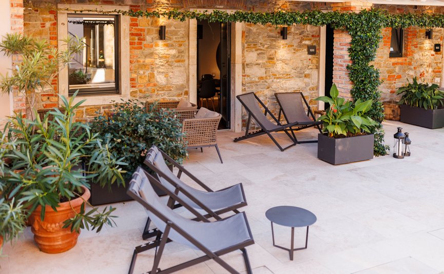Cozy patio with chairs, plants, and stone wall in the background