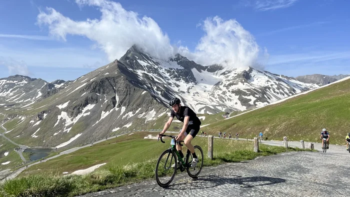 29. Glocknerkönig am 7. Juni 2026 © Tourismusverband BRUCK FUSCH GROSSGLOCKNER Radfahrer auf Bergstraße vor schneebedeckten Gipfeln und blauem Himmel