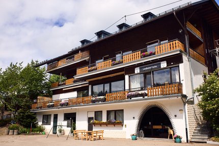 Landhotel mit Holzbalkonen und Blumendekoration an sonnigem Tag