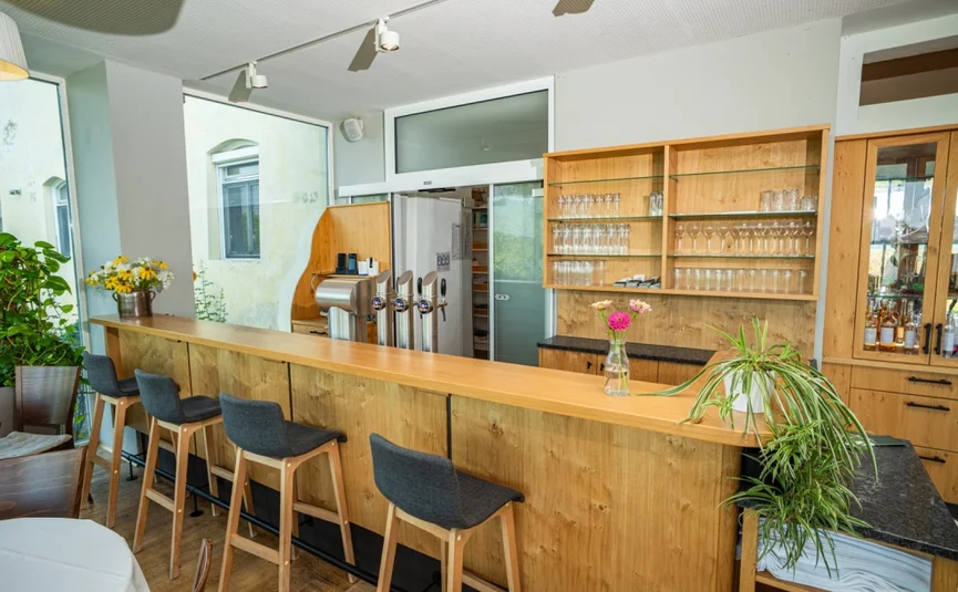 Helle Bar mit Holzmöbeln, Hockern und Zapfhähnen in gemütlichem Ambiente