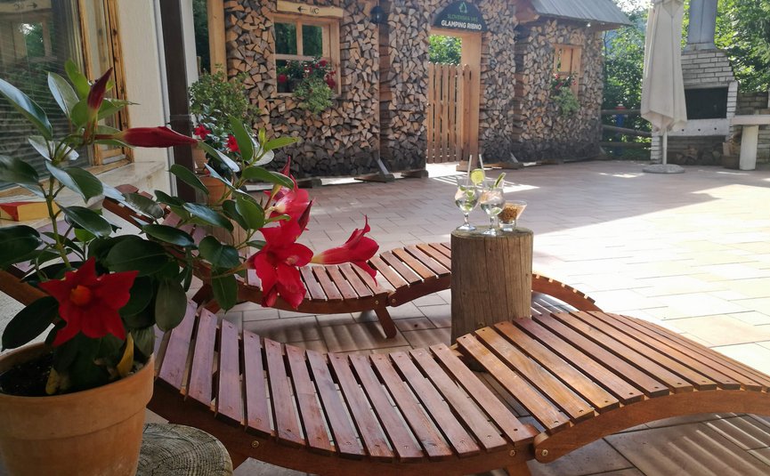 Lettini con bevande e casa di legno sullo sfondo al Glamping Ribno