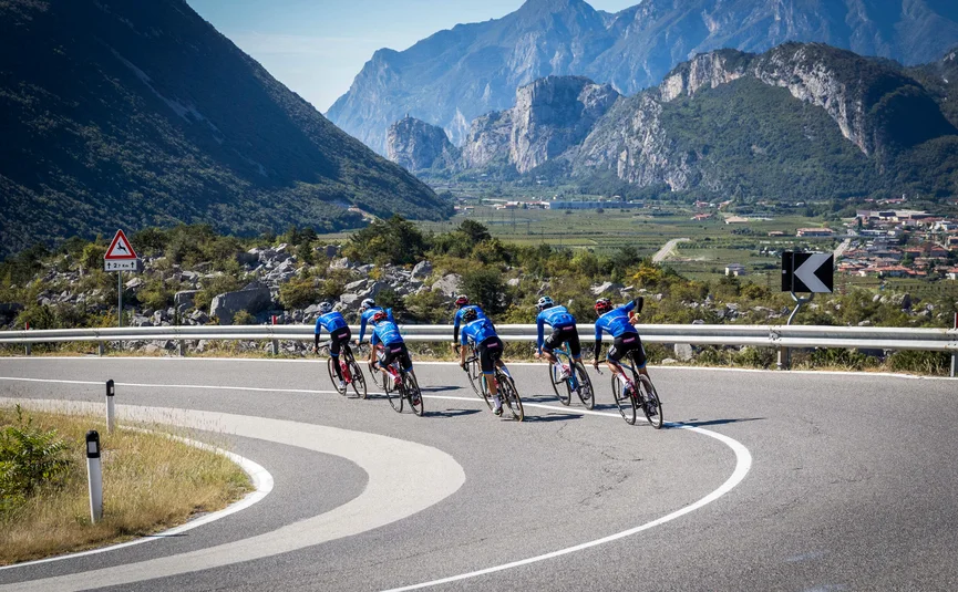 Sei ciclisti su una strada di montagna con montagne sullo sfondo
