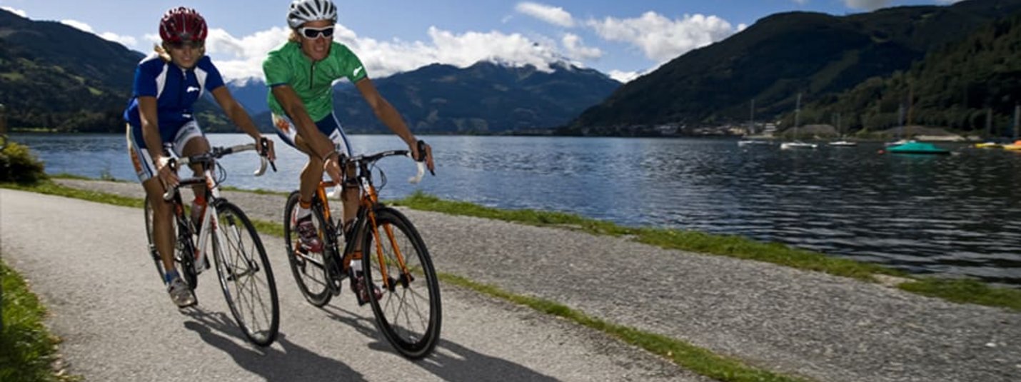 Due ciclisti su un sentiero accanto a un lago in zona montuosa