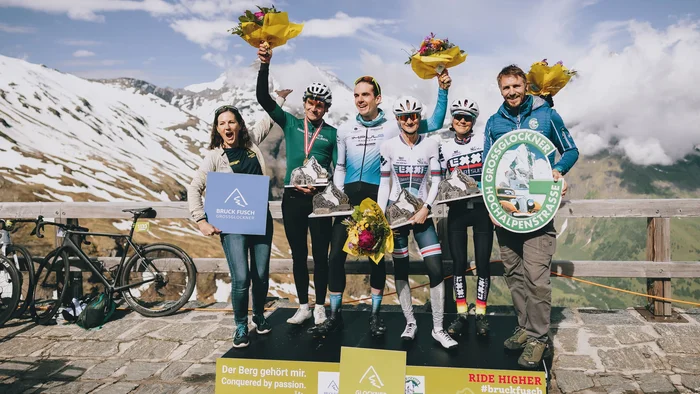 Glocknerkönig 2026 © BRUCK FUSCH GROSSGLOCKNER JFK Photography Sieger eines Radrennens mit Blumen und Trophäen auf Bergplattform