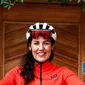 Isabella Felder © Gämsle Hotel Wirtshaus Woman in red cycling outfit gives thumbs up in front of wooden door with bike