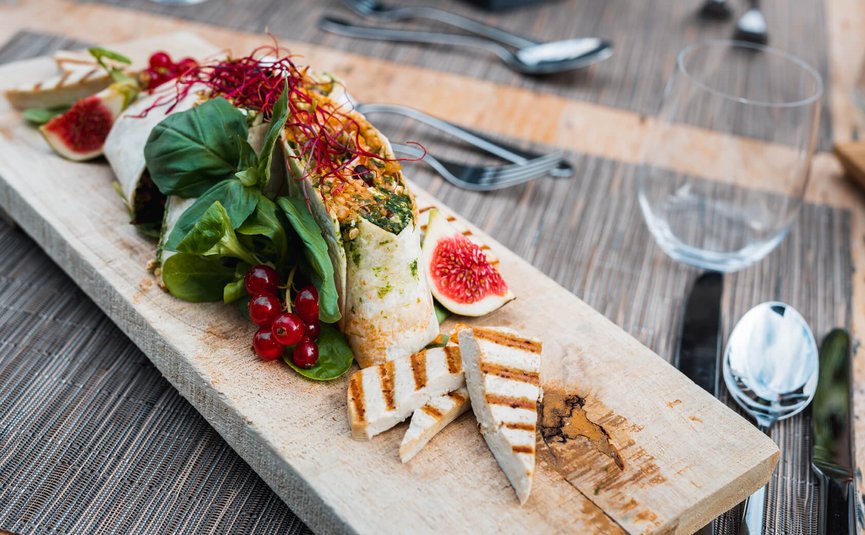 Vegan wraps with grilled tofu, fresh figs, and greens on wooden board
