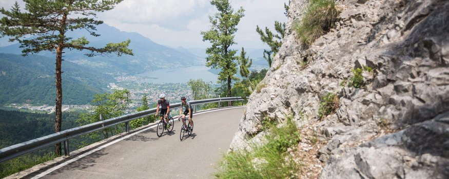 Cristallo Sport & Wellness Hotel **** © Heiko Mandl Zwei Radfahrer fahren auf einer Bergstraße mit Blick auf See und Berge