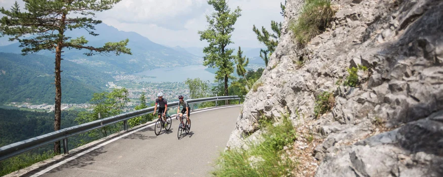 Cristallo Sport & Wellness Hotel **** © Heiko Mandl Zwei Radfahrer fahren auf einer Bergstraße mit Blick auf See und Berge