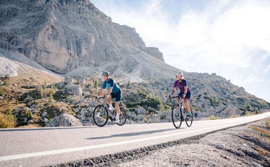 Two cyclists riding on a mountain road in sunny weather