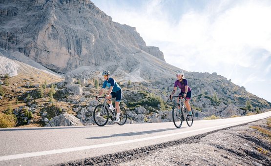 Two cyclists riding on a mountain road in sunny weather