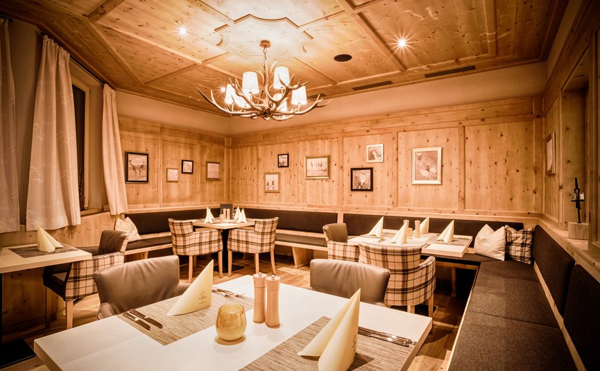 Cozy dining area with wooden walls and antler chandelier