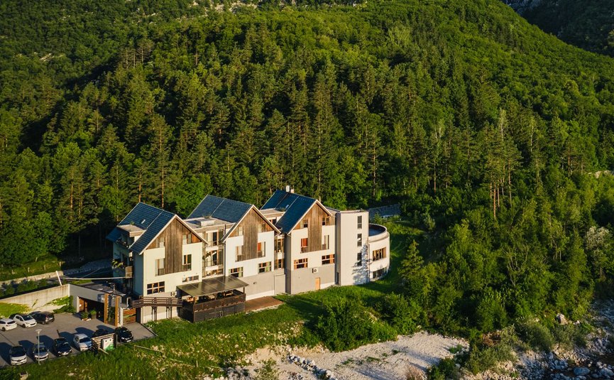 Hotel Boka *** © Hotel Boka Haus vor bewaldeten Bergen und Wasserfall im Tal