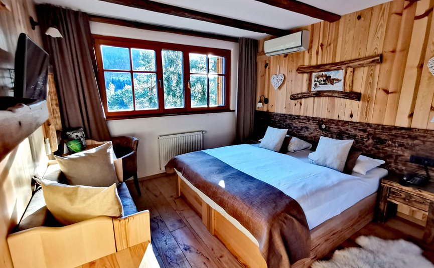 Camera da letto accogliente in legno con letto matrimoniale e vista montagna
