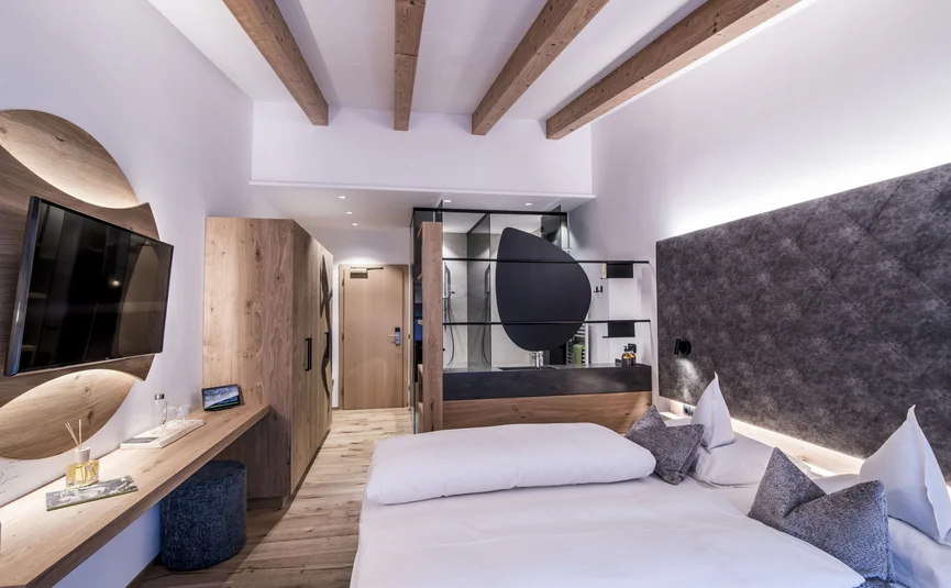 Modernes Hotelzimmer mit Holzdecke, Doppelbett und Fernseher an der Wand