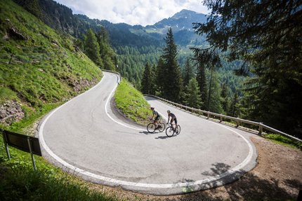 Twee wielrenners in sportkleding op een kronkelende bergweg
