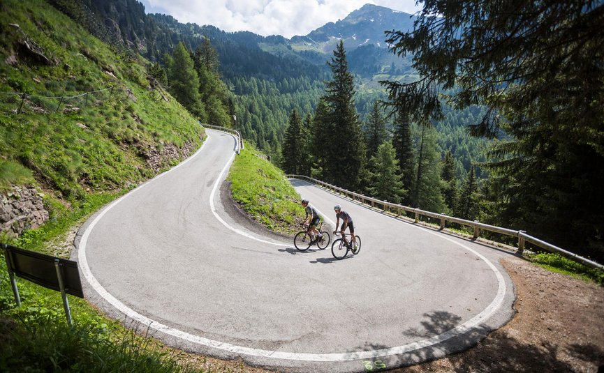 Due ciclisti in abbigliamento sportivo su una strada tortuosa in montagna