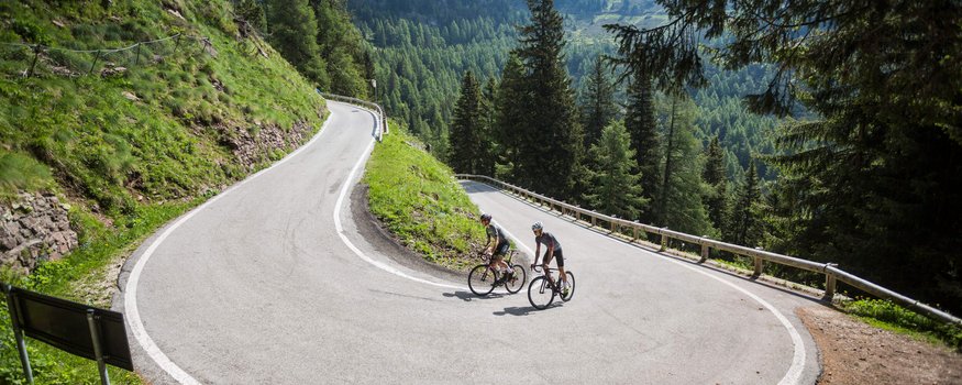 Due ciclisti in abbigliamento sportivo su una strada tortuosa in montagna