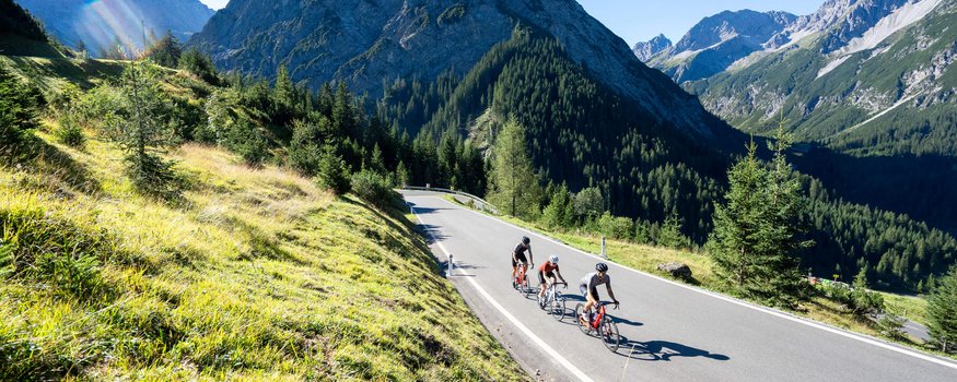 3 Highlights für deinen Rennradurlaub im Tannheimer Tal © Christina Neubauer Drei Radfahrer auf Bergstraße umgeben von Bergen und grünem Gras