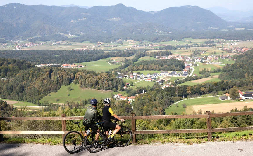 Zwei Radfahrer bei Aussicht auf Dorf und Berge im sonnigen Tal