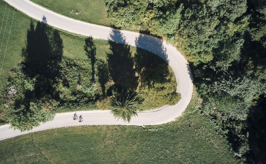 Vista aerea di due ciclisti su strada curva tra paesaggio verde