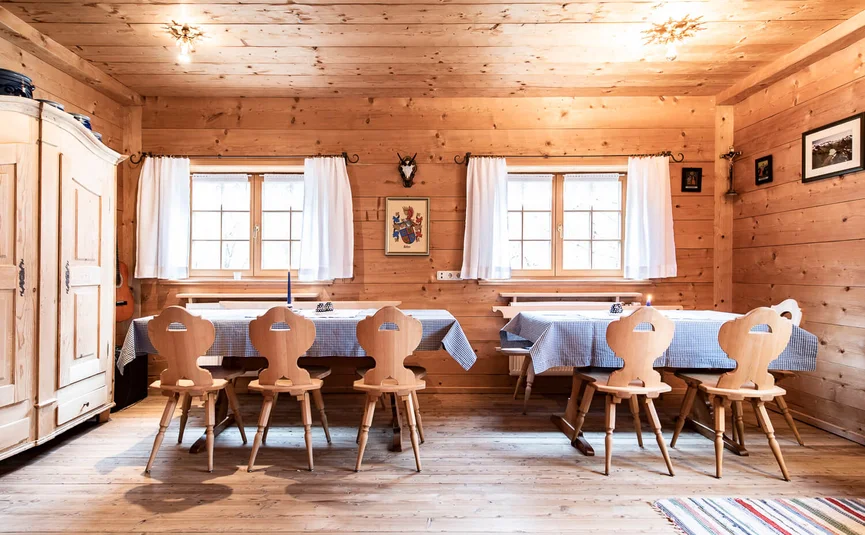 Gämsle Hotel, Wirtshaus & mehr .. © Raffael F. Lehner Rustic dining area with wooden chairs and checkered tablecloths in a wooden cabin