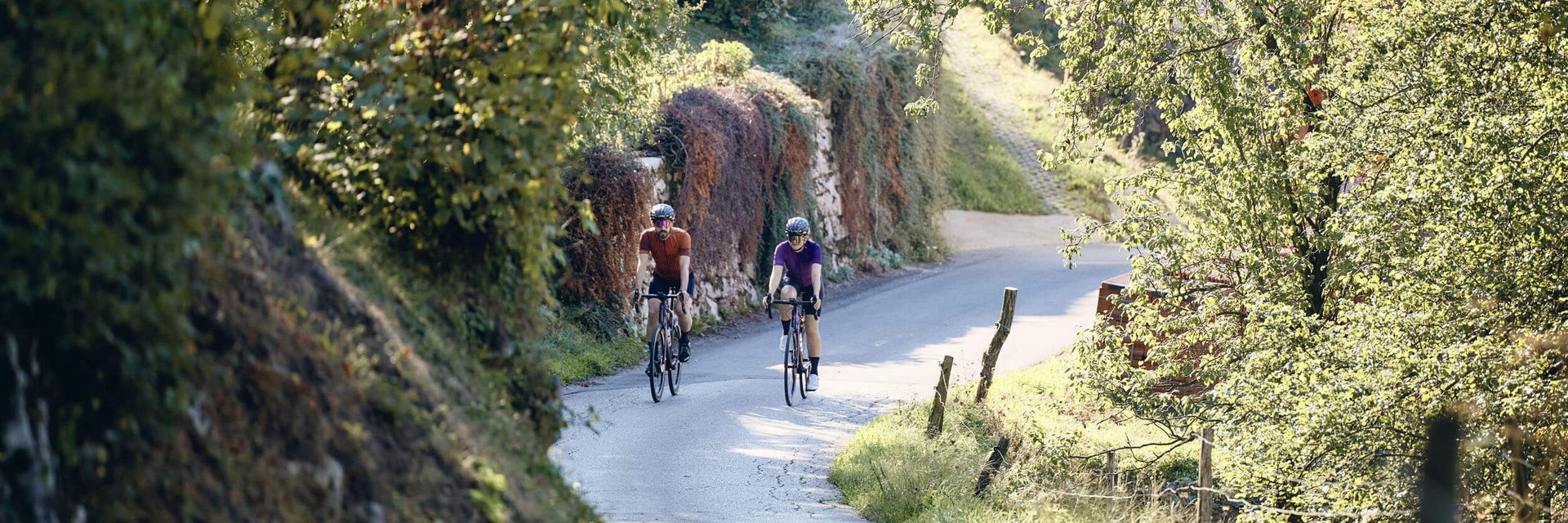 Landrefugium Obermüller ****S © Tobias Köhler Zwei Radfahrer auf einem sonnigen Landweg mit grünen Bäumen