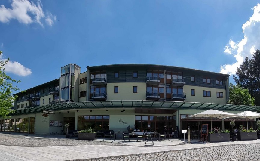 Vista di un edificio moderno con area esterna e ombrelloni sotto un cielo azzurro