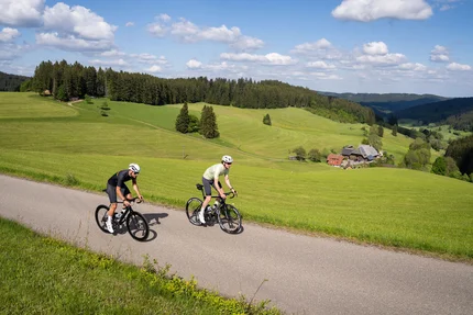 Baden-Württemberg © Baschi Bender Two cyclists riding on a country road through green hills and forests