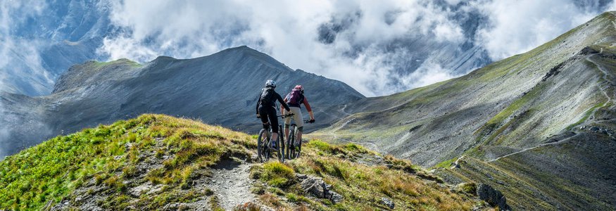 Zwei Mountainbiker fahren auf einem Bergpfad mit Nebelschwaden