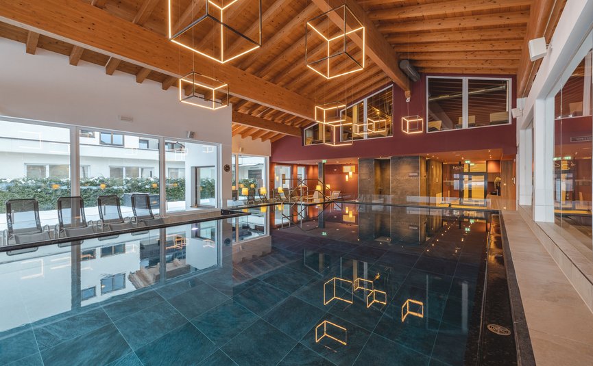 Indoor pool with wooden beam ceiling and cube-shaped lights