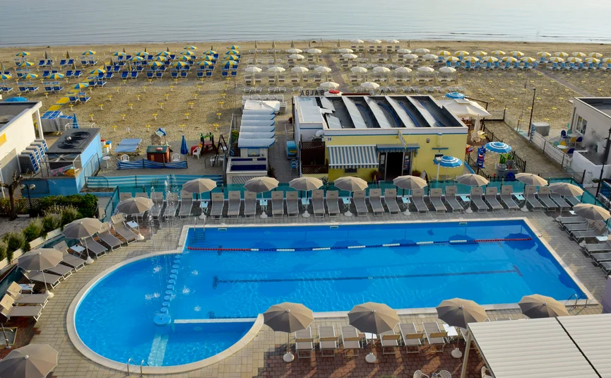 Leeg zwembad met parasols en ligstoelen bij het strand
