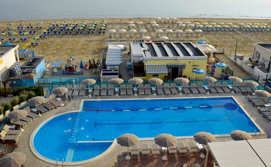 Empty pool with umbrellas and lounge chairs by the beach