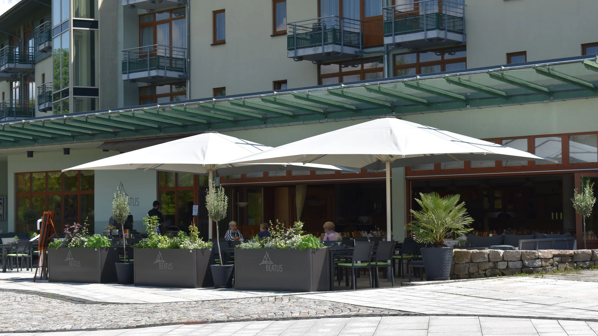 7 Reasons to Roadbike @Erzgebirge © Hotel Am Kurhaus Außenterrasse eines Cafés mit weißen Sonnenschirmen und Sitzplätzen