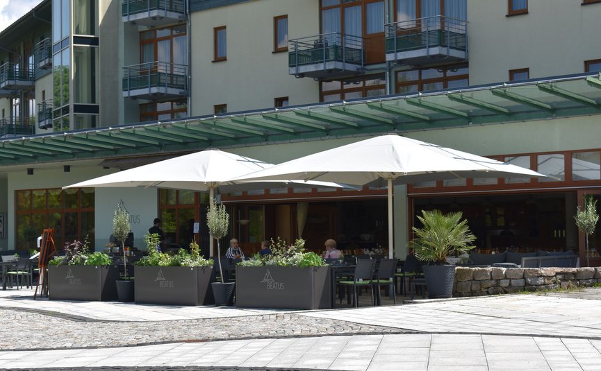 Terrazza esterna di un caffè con ombrelloni bianchi e sedute