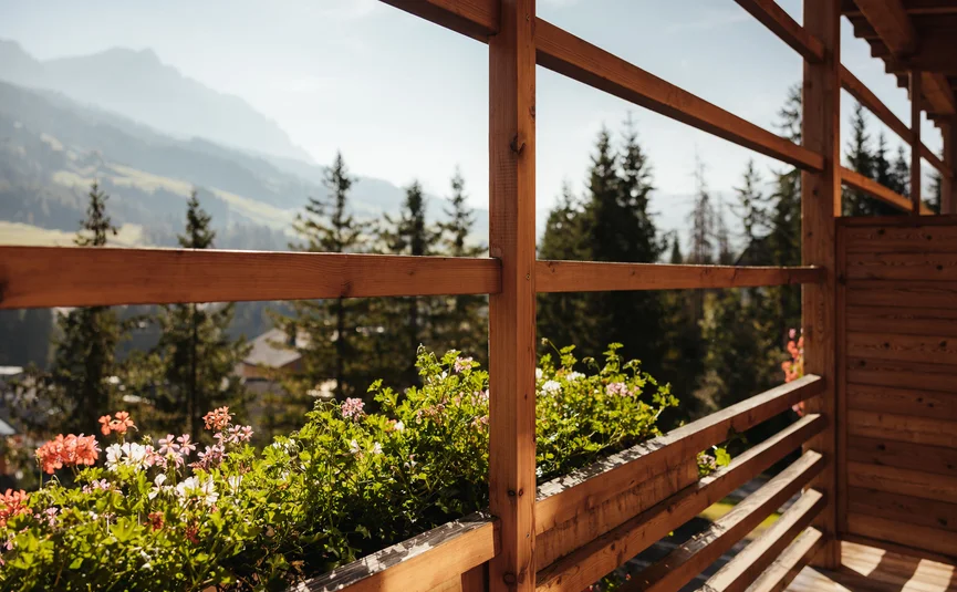 Balcone con ringhiera in legno e fiori con vista su montagne e alberi