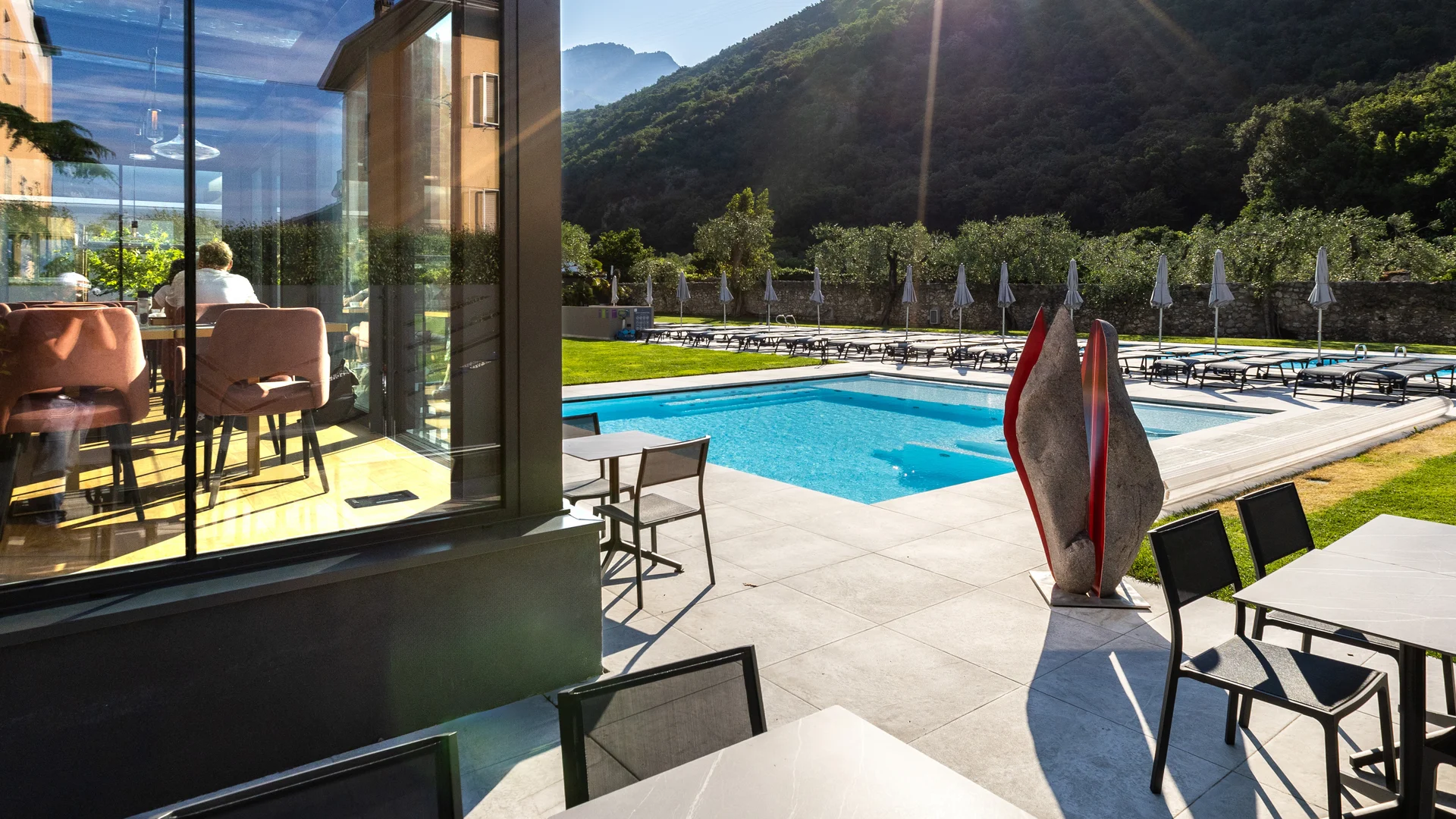 Dolce Vita tanken im AktivHotel Santa Lucia © Fabio Staropoli Sonniger Poolbereich mit Liegestühlen, Tischen und Bergblick