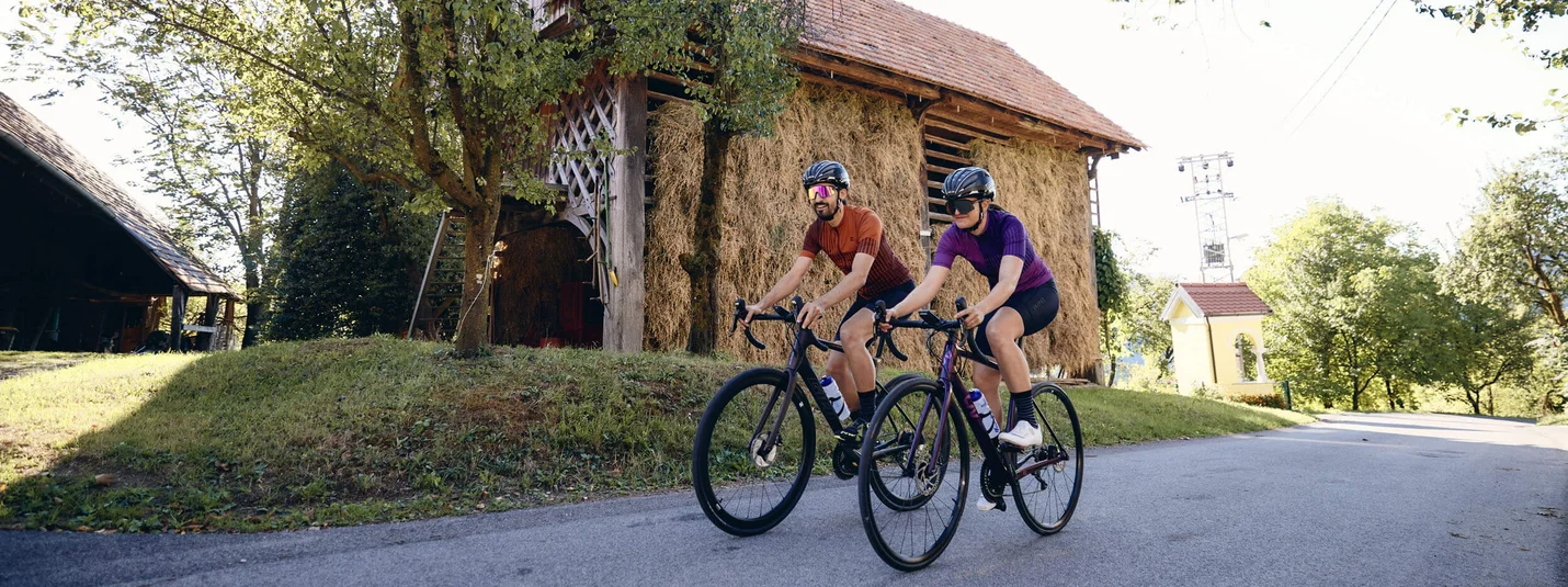 Upper and Lower Savinja Valley road bike tour © Tobias Köhler Two cyclists riding on rural road near hay barn and trees