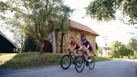 Breeze, Pulse oder Peak? 20 neue Traumrouten im Slowenischen Istrien © Tobias Köhler Zwei Radfahrer fahren auf Landstraße neben Heuboden und Bäumen