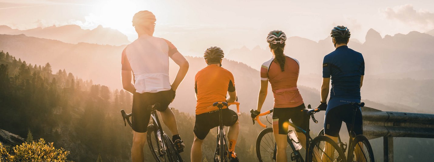 Four cyclists overlooking mountain landscape at sunset