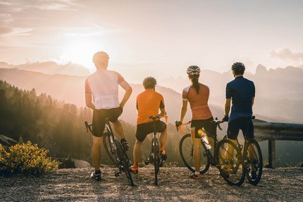 Four cyclists overlooking mountain landscape at sunset
