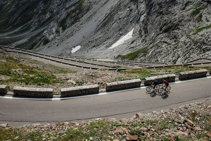 Twee fietsers op kronkelende bergweg met steile rotskliffen