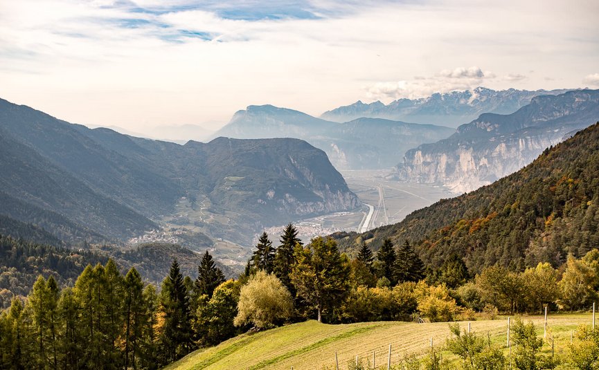 Vista di una valle boscosa con montagne e villaggi sullo sfondo