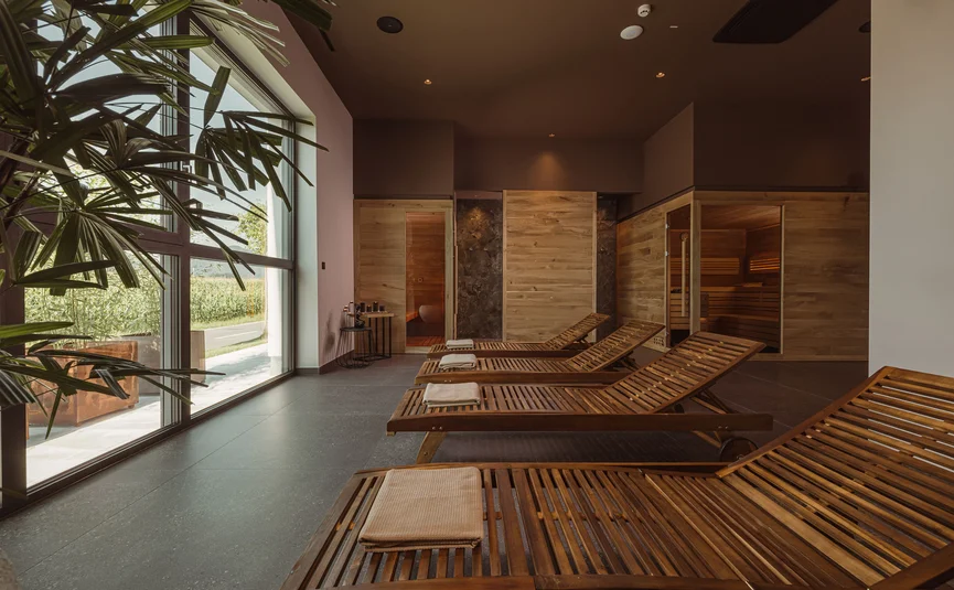 Ruheraum mit Holzliegen und Sauna in moderne Wellnessanlage