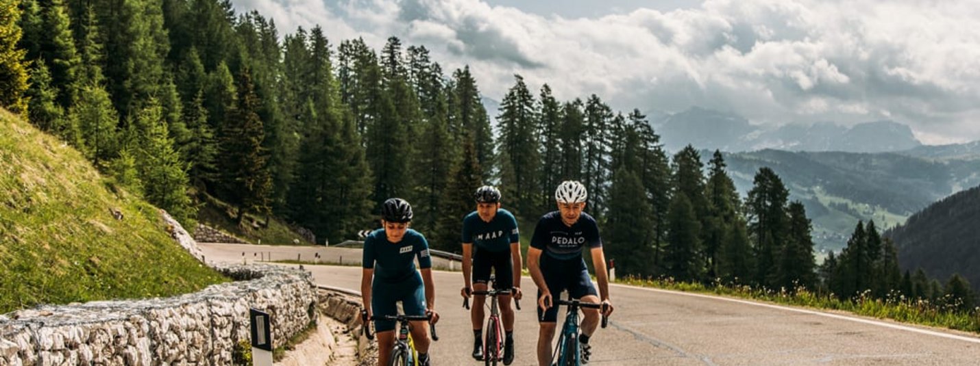 Tre ciclisti pedalano su una strada di montagna tortuosa in una zona boscosa