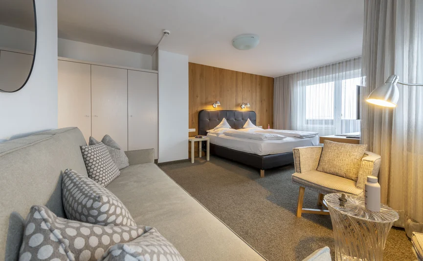 Camera d'hotel moderna con letto, divano e poltrona