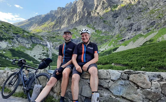Zwei Radfahrer sitzen auf einer Steinmauer in den Bergen mit Fahrrad neben ihnen